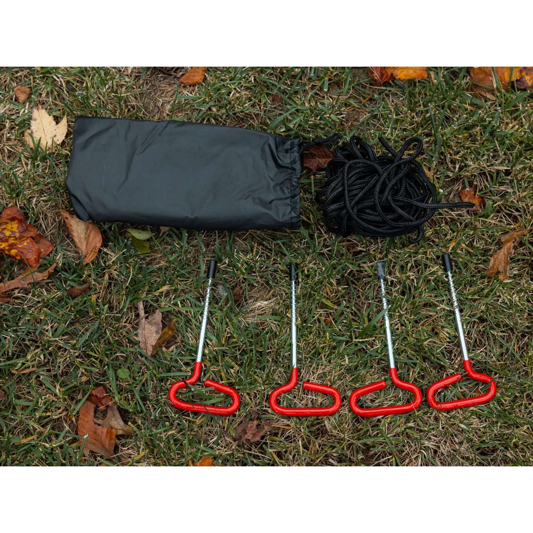 KYFE portable sauna tent ground stakes, tie down ropes, and carry bag laid out on grass – outdoor sauna tent anchoring and securing accessories