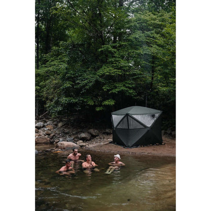 Group of men cold plunging in natural river beside arctic gray KYFE portable sauna tent in forest – outdoor sauna and cold plunge wellness routine